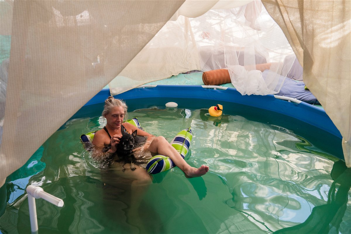 <i>Ariana Drehsler/Getty Images</i><br/>Dot of House of Dots art gallery relaxes in her pool with her dog as they cool off amid a heatwave on August 31 in Slab City