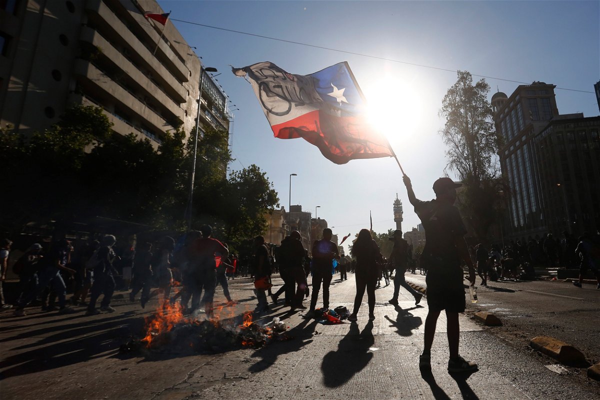 <i>Marcelo Hernandez/Getty Images</i><br/>A demonstrator waves the Chilean flag during a November 2020 protest against then President Sebastian Pinera in Santiago.