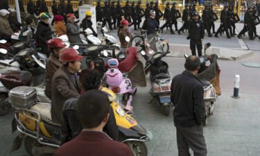 A UN report said the Chinese government's actions in Xinjiang may constitute "crimes against humanity." Residents watch security personnel armed with batons and shields patrolling through Kashgar
