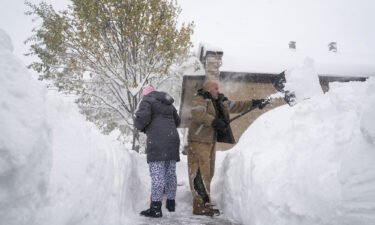 Jenny Vega (L) and Roberto Rentas shovel snow in front of their house in Buffalo