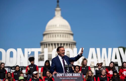Connecticut Democratic Sen. Chris Murphy speaks with students wearing body armor stand behind him on a stage during a gun safety reform rally near the Capitol Reflecting Pool in Washington