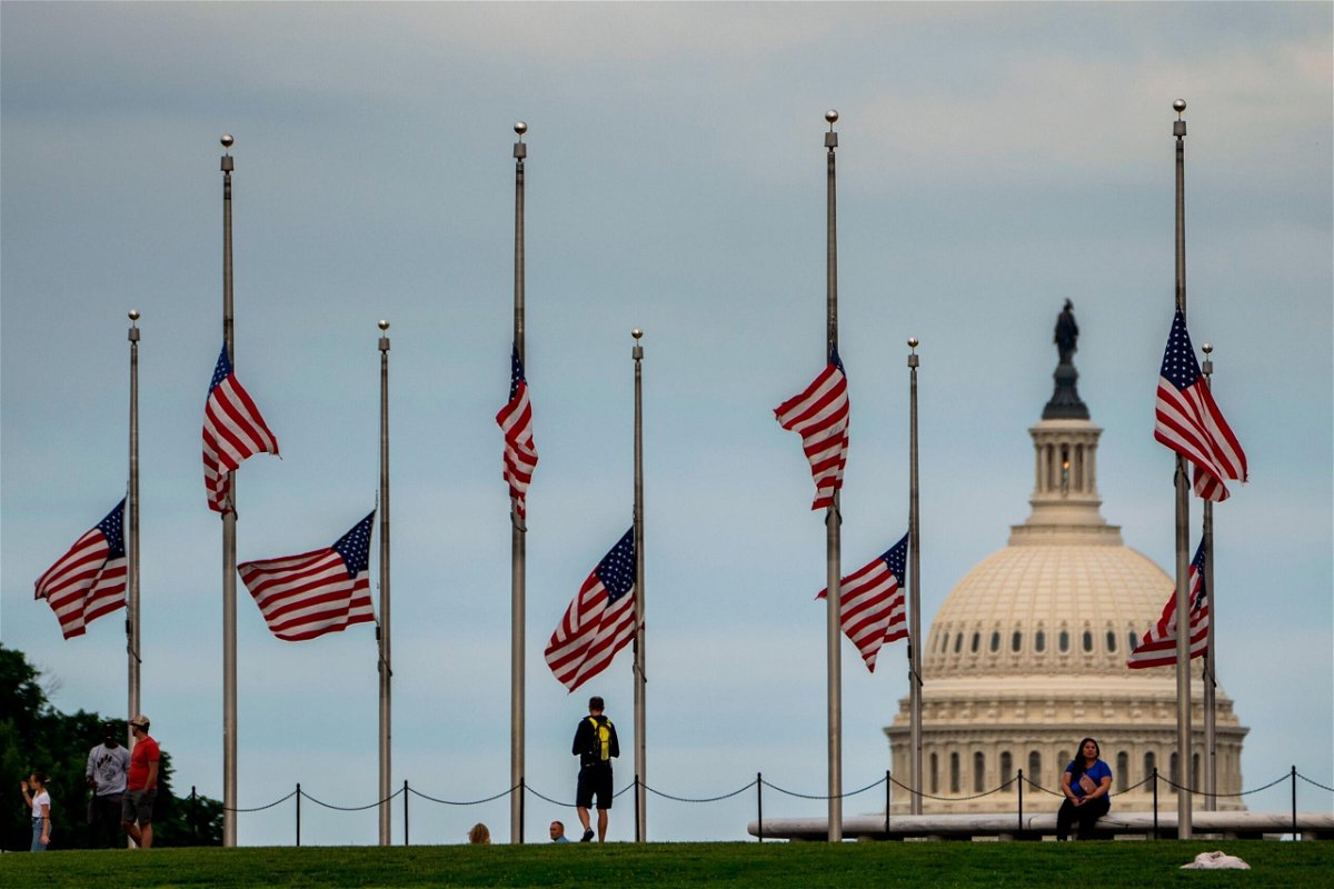 <i>Kent Nishimura/Los Angeles Times/Getty Images</i><br/>American flags are seen at half-staff surrounding the Washington Monument as people enjoy the weather on the National Mall on Wednesday