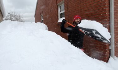 Patrick Harden clears snow from the roof of his car in Erie