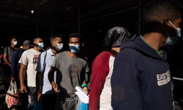 A group of migrants wait in line after arriving from Texas