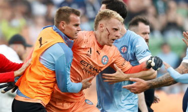 Tom Glover of Melbourne City is escorted from the pitch by teammates after fans stormed the pitch during the game against Melbourne Victory.