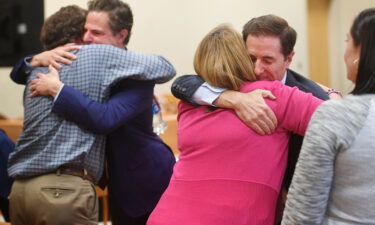 Plaintiff William Sherlach hugs attorney Josh Koskoff while plaintiff Nicole Hockley hugs attorney Chris Mattei following the jury verdict and reading of monetary damages in the Alex Jones defamation trial in Waterbury