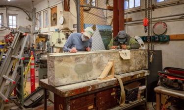 Workers are seen etching the inscription on the perimeter wall.