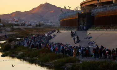 Migrants queue near the border wall in El Paso to turn themselves in to Border Patrol agents and request asylum in the US.