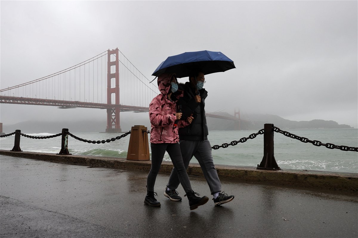 A couple walks near the Golden Gate Bridge as rain hits San Francisco this week.