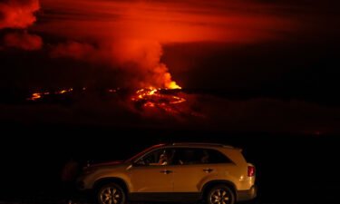 A man talks on a phone in his car alongside Saddle Road as the Mauna Loa volcano erupts near Hilo