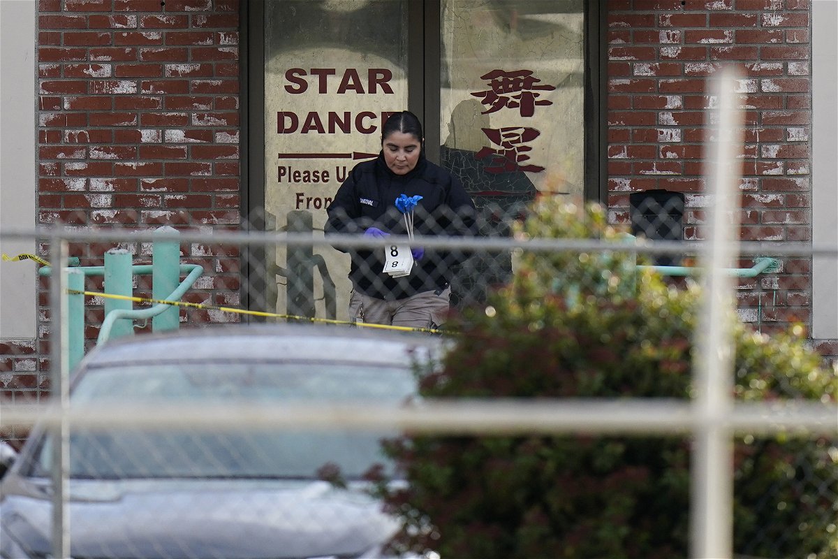 An investigator carries markers outside Star Dance Studio in Monterey Park
