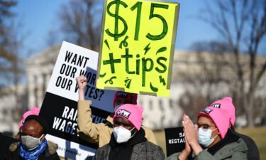 An activist holds a placard demanding a $15 an hour minimum wage and tips for restaurant workers during a rally at the US Capitol on February 8