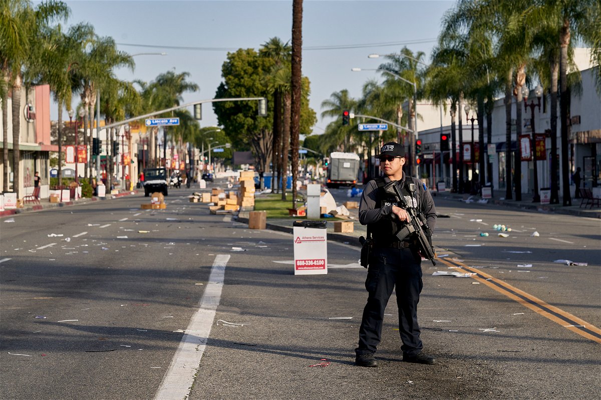 A Monterey Park police officer stands guard near where vendor tents once stood for the Lunar New Year festival near the Star Dance Studio in Monterey Park