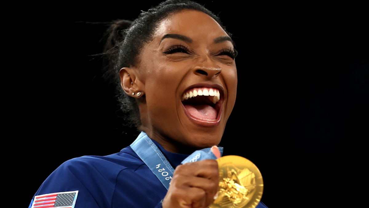 Simone Biles poses with her gold medal from the team final at the 2024 Paris Olympics.