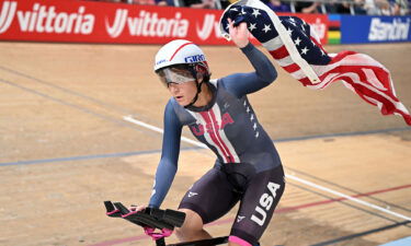 Chloe Dygert rides around a track while holding U.S. flag