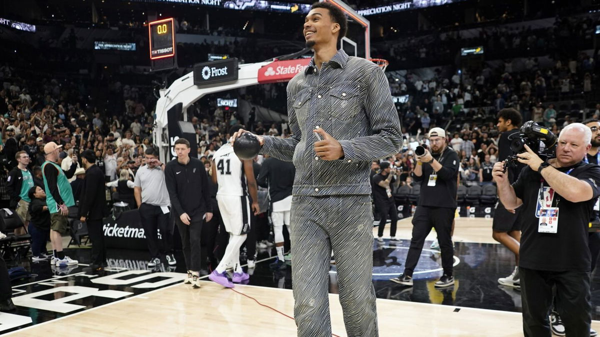 San Antonio Spurs forward Victor Wembanyama prepares to throw a ball to fans after the final game of the season.