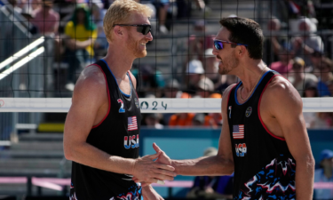 Miles Evans and Chase Budinger celebrate defeating France in a beach volleyball match during the Paris Olympic Games at Eiffel Tower Stadium.