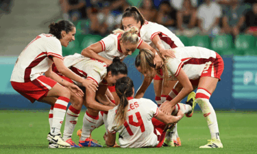 Canadian players celebrate over a stunned scorer Vanessa Gilles late in a win over France at the 2024 Paris Olympics