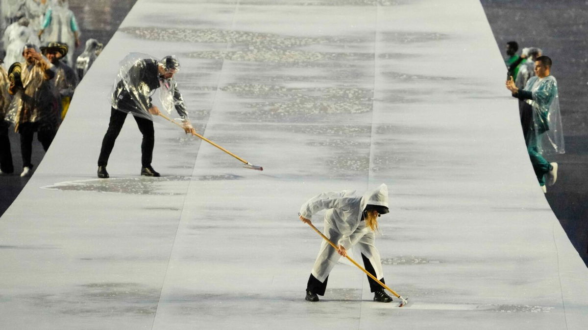 A worker dries the stage in the Trocadero as rain falls during the Opening Ceremony for the Paris 2024 Olympics.