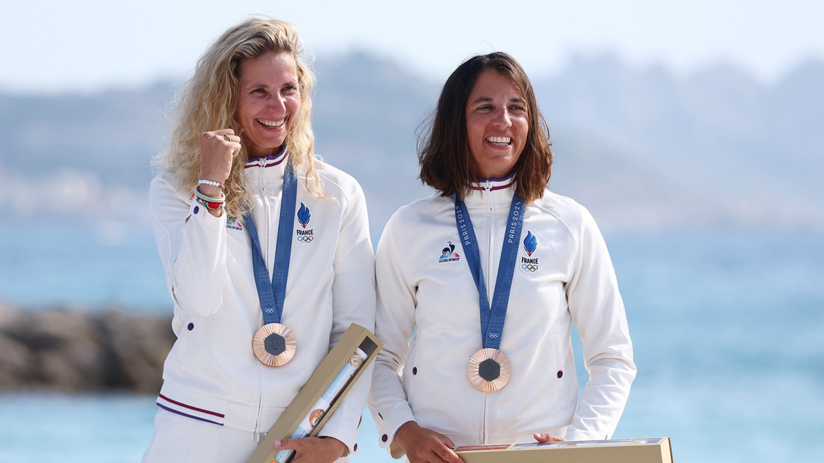 Bronze medalists Sarah Steyaert and Charline Picon of Team France celebrate at the medal ceremony of the Women's Skiff 49erFX.