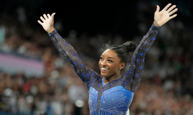 Simone Biles waves to the crowd after finishing her beam routine during the women's all-around final at the Paris 2024 Olympics.