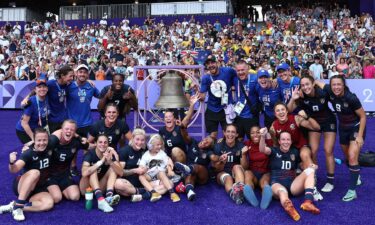 U.S. women's rugby team pose for a photo with the bell following their bronze medal win.