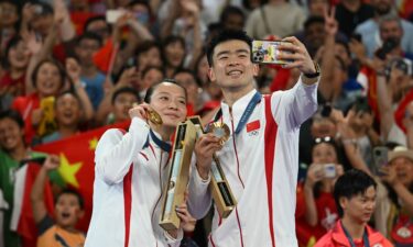 China's Gold medalists Zheng Siwei (R) and Huang Ya Qiong pose for a selfie on the podium at the mixed doubles badminton medal ceremony during the Paris 2024 Olympics at Porte de la Chapelle Arena in Paris on August 2