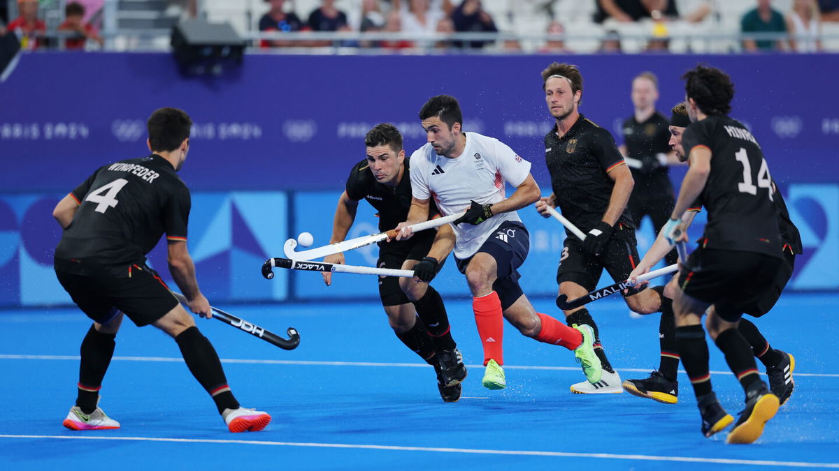 Lee Morton of Great Britain controls the ball under pressure from Germany during the men's Pool A match on day seven of the Paris Olympics at Stade Yves Du Manoir on August 02