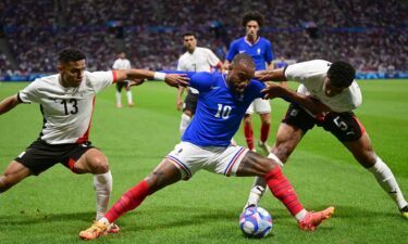 French forward Alexandre Lacazette fights for the ball with Egypt defenders Karim El Debes and Hossam Abdelmaguid during a men's semifinal match between France and Egypt during the Paris 2024 Olympic Games at the Lyon Stadium on August 5