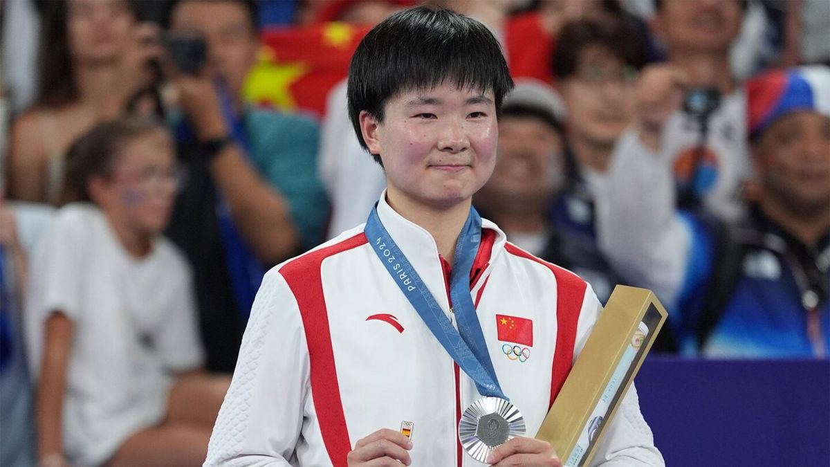 China's silver medalist He Bingjiao celebrates on the podium during the medal ceremony after the Badminton - Women's Singles Gold Medal Match