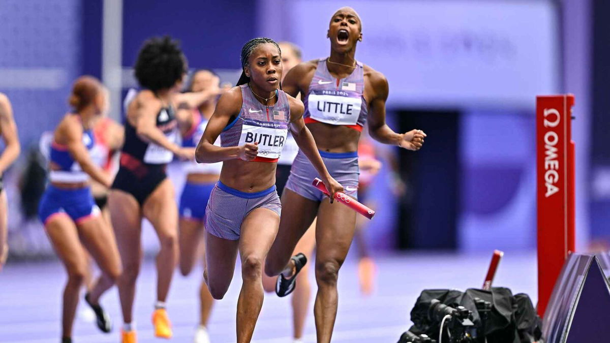 Aaliyah Butler of Team United States receives the baton from Shamier Little during the women's 4 x 400m relay round 1 at the Stade de France.