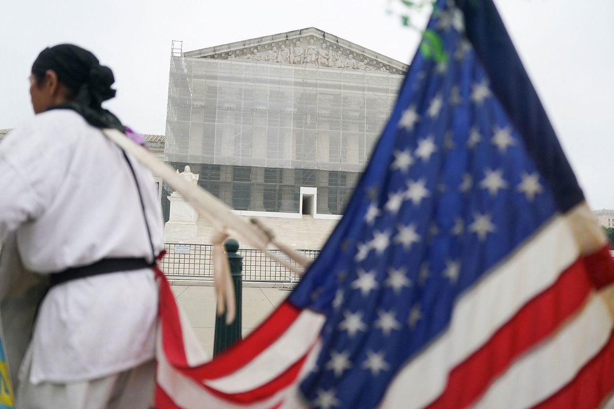 <i>Nathan Howard/Reuters via CNN Newsource</i><br/>A person stands with a U.S. flag attached to them outside the U.S. Supreme Court in Washington