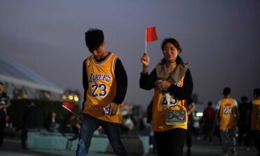 A woman and a man in LeBron James jerseys hold Chinese national flags before an NBA exhibition game between the Brooklyn Nets and Los Angeles Lakers in Shanghai in 2019.