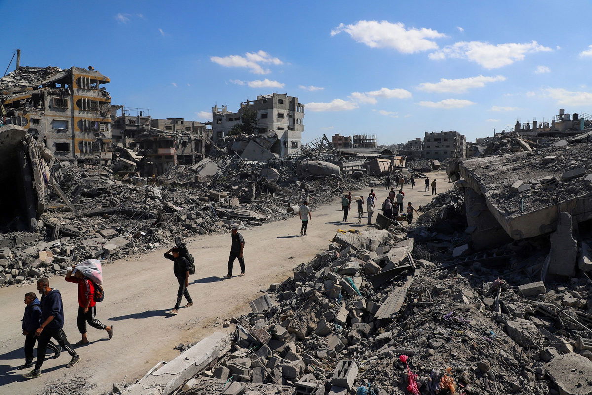 <i>Ebrahim Hajjaj/Reuters via CNN Newsource</i><br/>Palestinians walk past the rubble of destroyed buildings in Gaza City